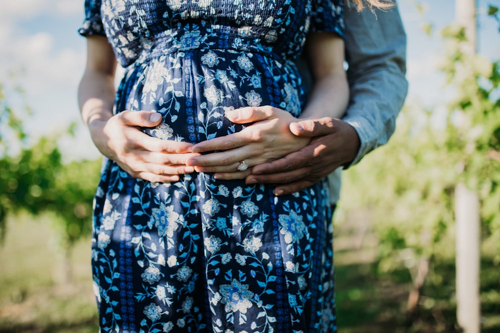 selective focus photography of man back hugging pregnant woman