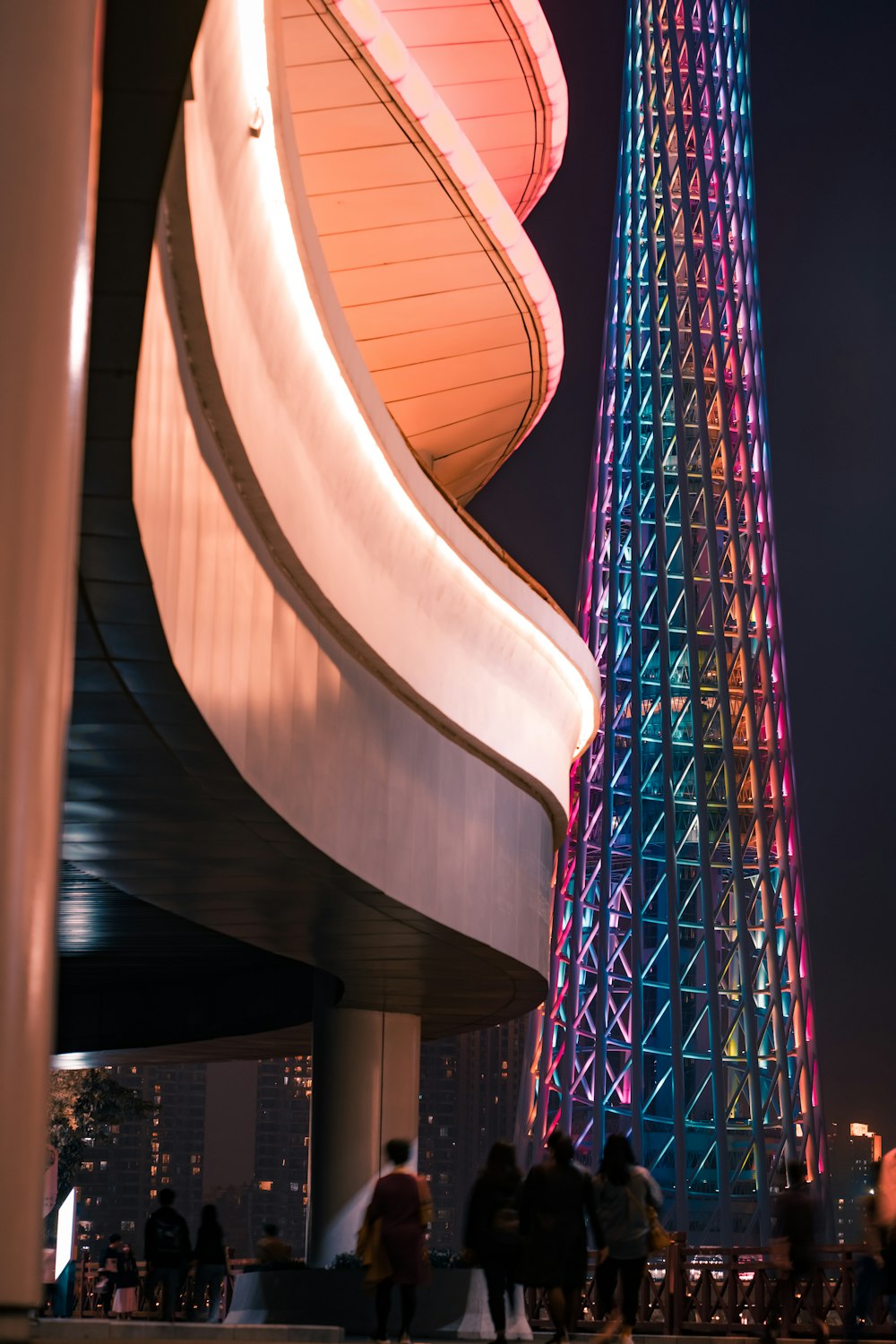 夜に明かりのついた建物の横を歩く群衆