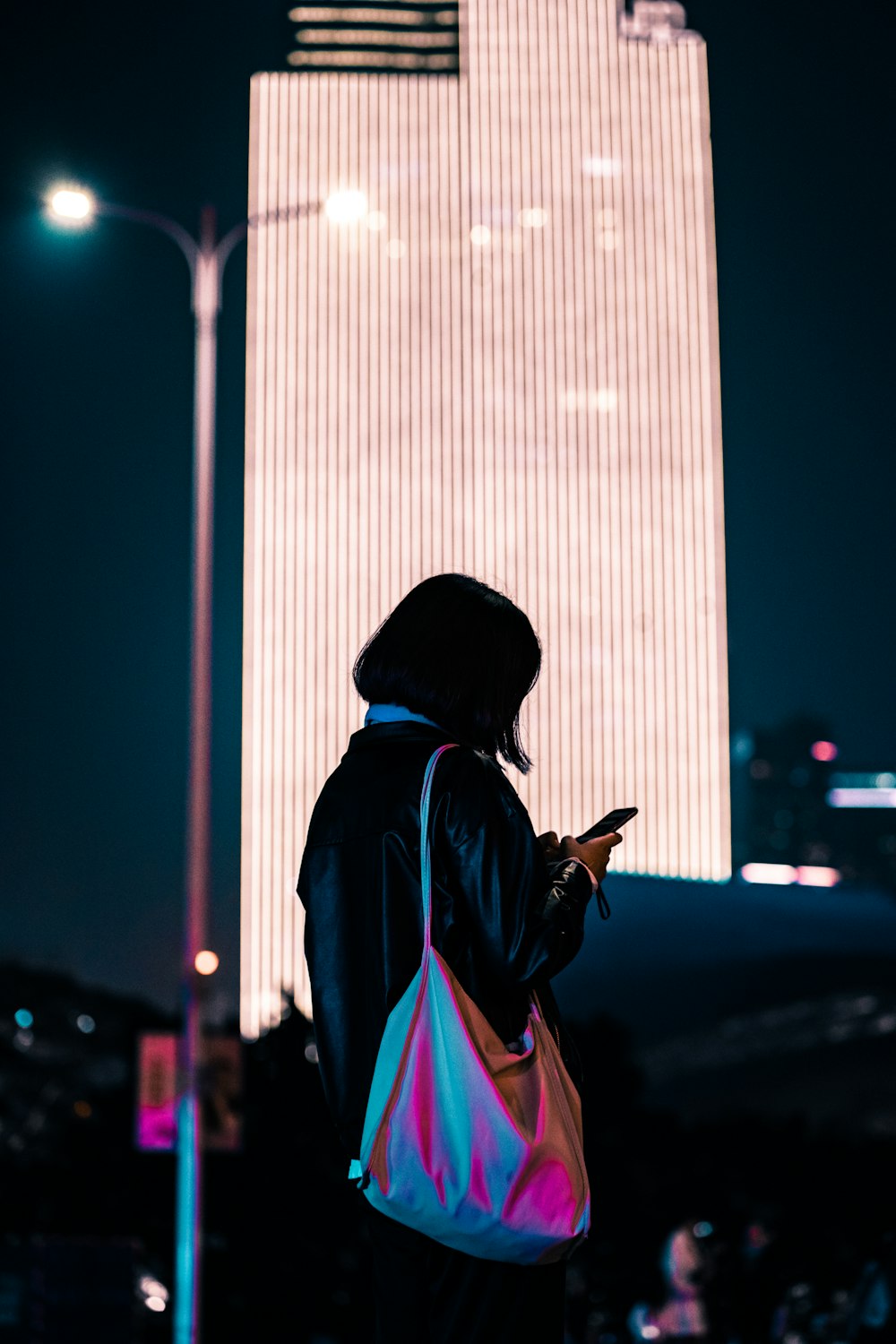 woman wearing black leather jacket using phone while standing