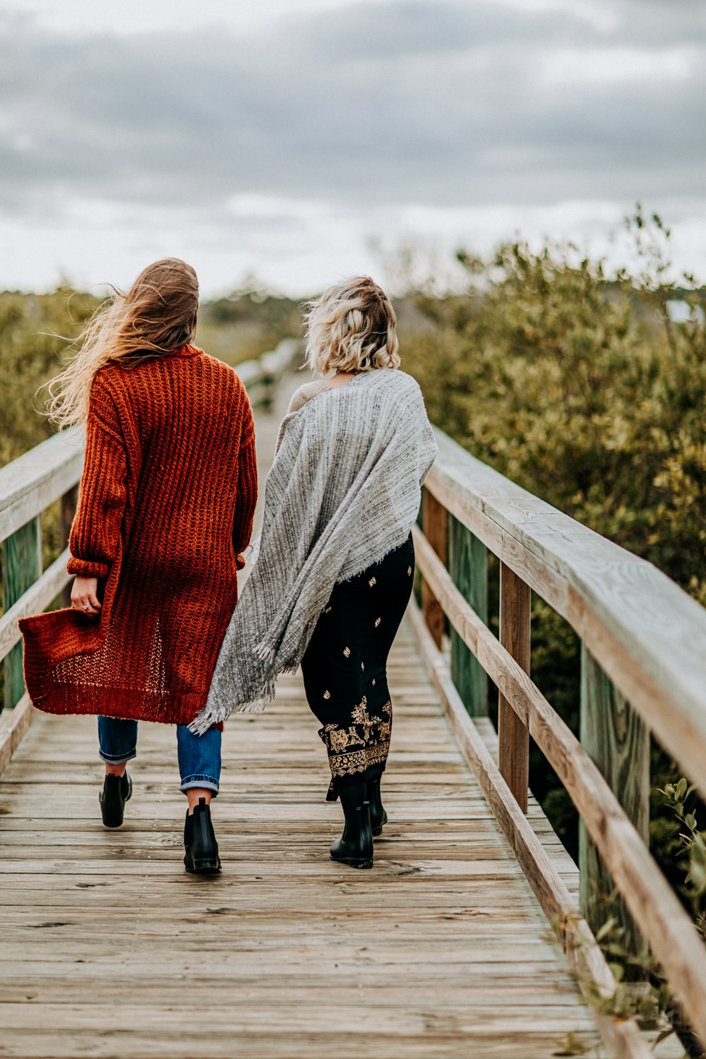 two women walking on wooden bridge