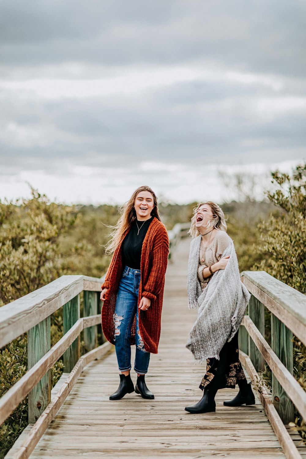 two laughing women on brown wooden bridge