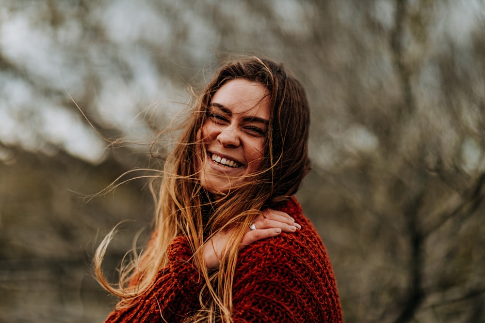 selective focus photography of smiling woman wearing brown sweater