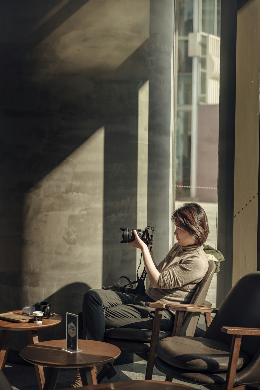 woman sitting on chair using DSLR camera