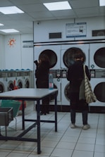 A friendly staff member assisting a customer at a bright, modern Zips Washers franchise outlet.