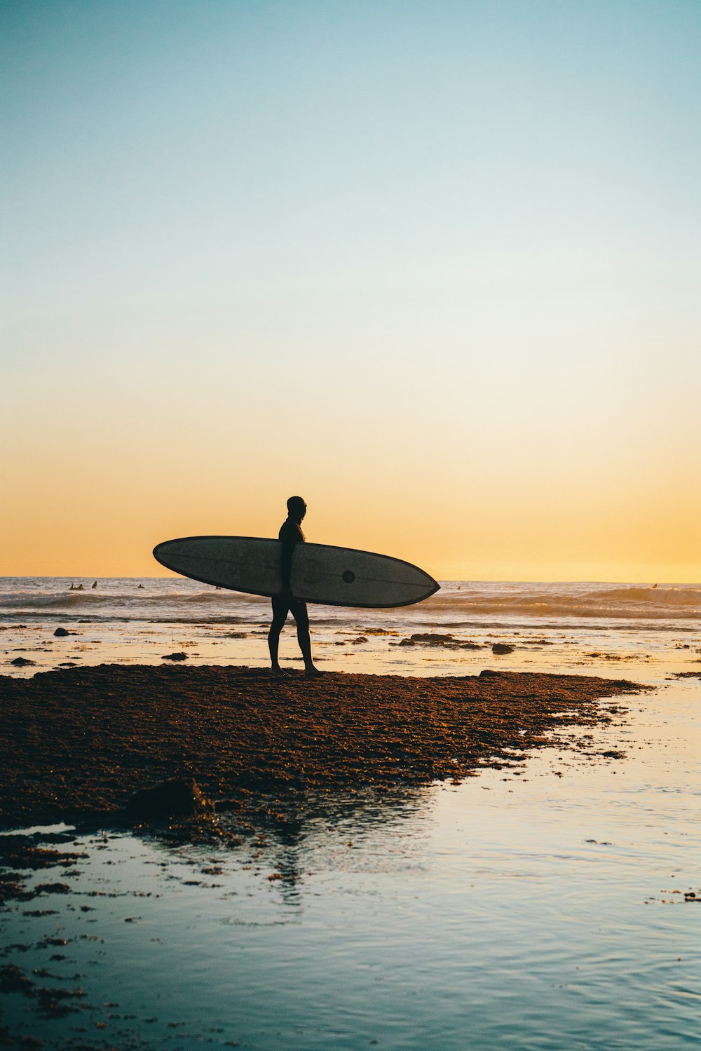 homme tenant une planche de surf blanche