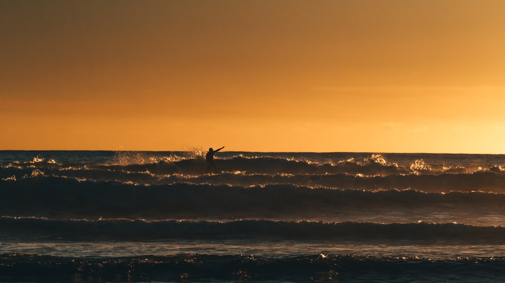 man in sea during golden hour