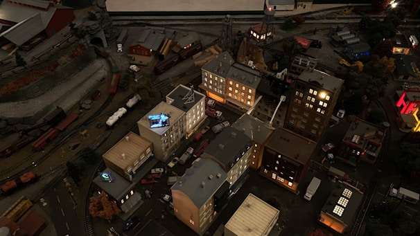 Evening scene of a 1/64 scale diorama illuminated with tiny street lamps and glowing windows.