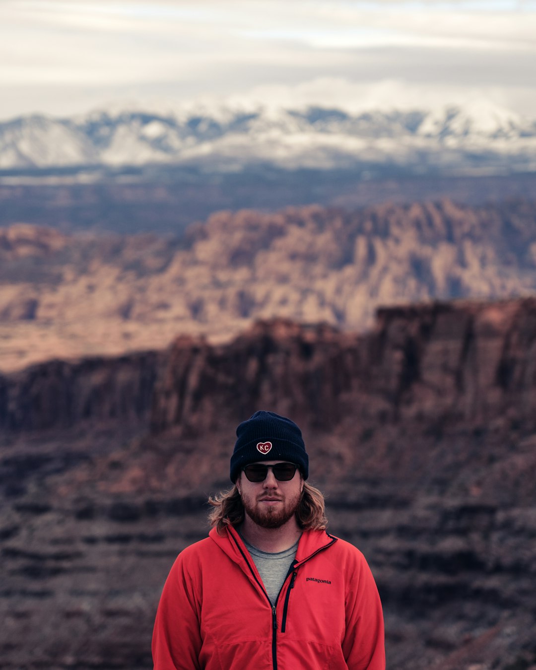 man wearing red zip jacket near mountains during day