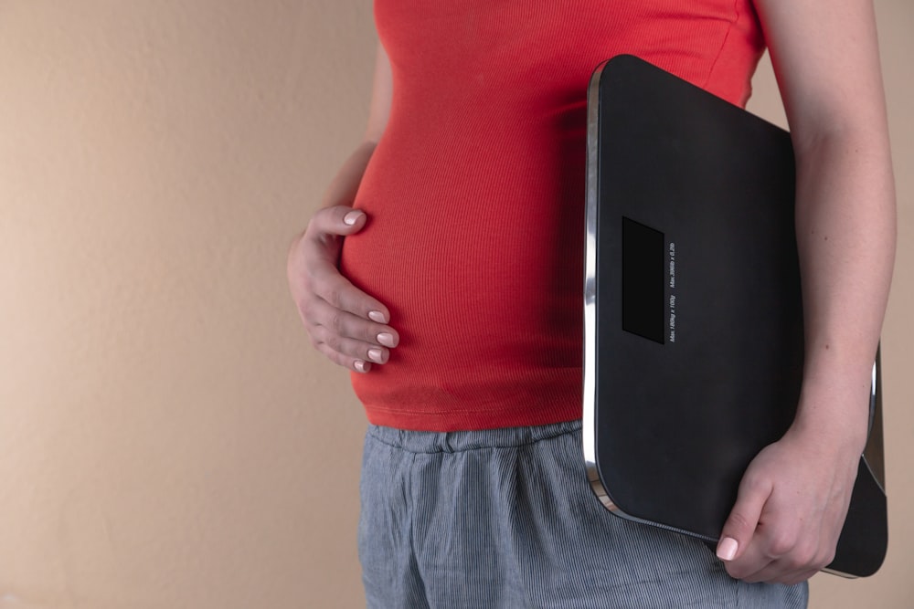 mulher grávida tocando sua barriga e carregando uma cale de banheiro digital