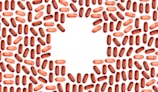 Numerous red and pink capsules are arranged in a pattern that forms the shape of a heart in the center of the image with a white background.