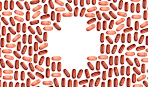Numerous red and pink capsules are arranged in a pattern that forms the shape of a heart in the center of the image with a white background.