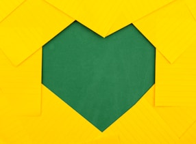 yellow papers forming green heart hole