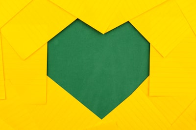 yellow papers forming green heart hole visit teams background