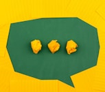 three crumpled yellow papers on green surface surrounded by yellow lined papers