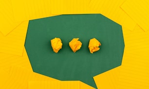 three crumpled yellow papers on green surface surrounded by yellow lined papers