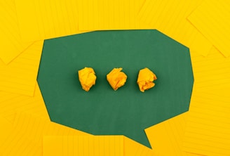 three crumpled yellow papers on green surface surrounded by yellow lined papers