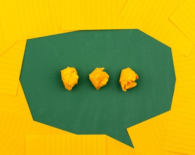 three crumpled yellow papers on green surface surrounded by yellow lined papers