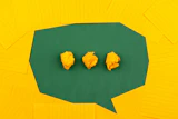 three crumpled yellow papers on green surface surrounded by yellow lined papers
