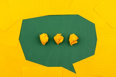 three crumpled yellow papers on green surface surrounded by yellow lined papers visit google meet background