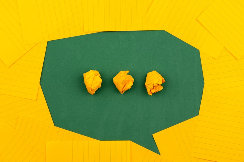 three crumpled yellow papers on green surface surrounded by yellow lined papers