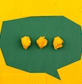 three crumpled yellow papers on green surface surrounded by yellow lined papers