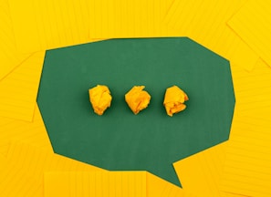 three crumpled yellow papers on green surface surrounded by yellow lined papers