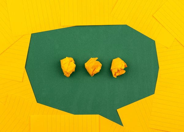 three crumpled yellow papers on green surface surrounded by yellow lined papers