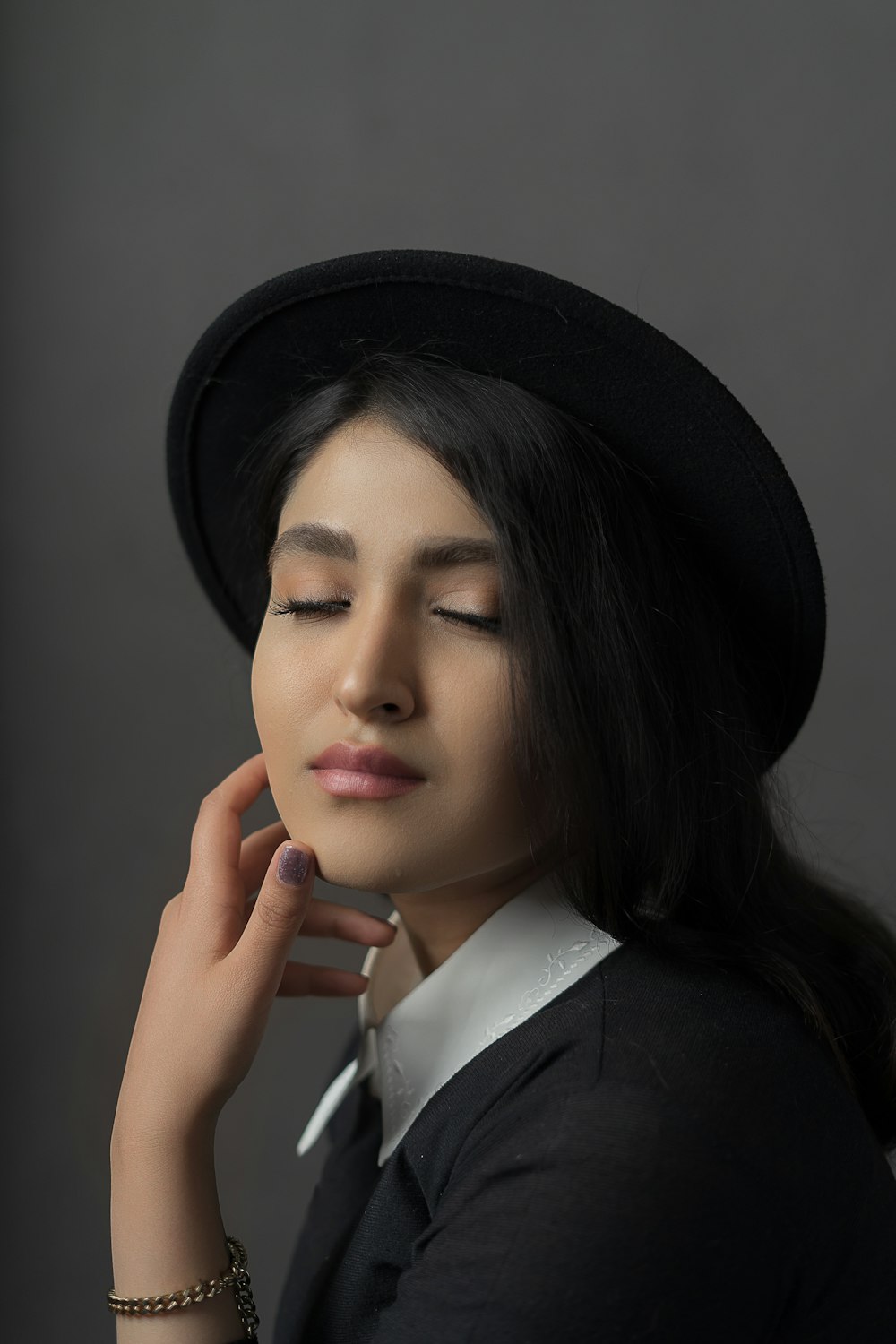 Eine Frau, die einen schwarzen Hut mit geschlossenen Augen trägt