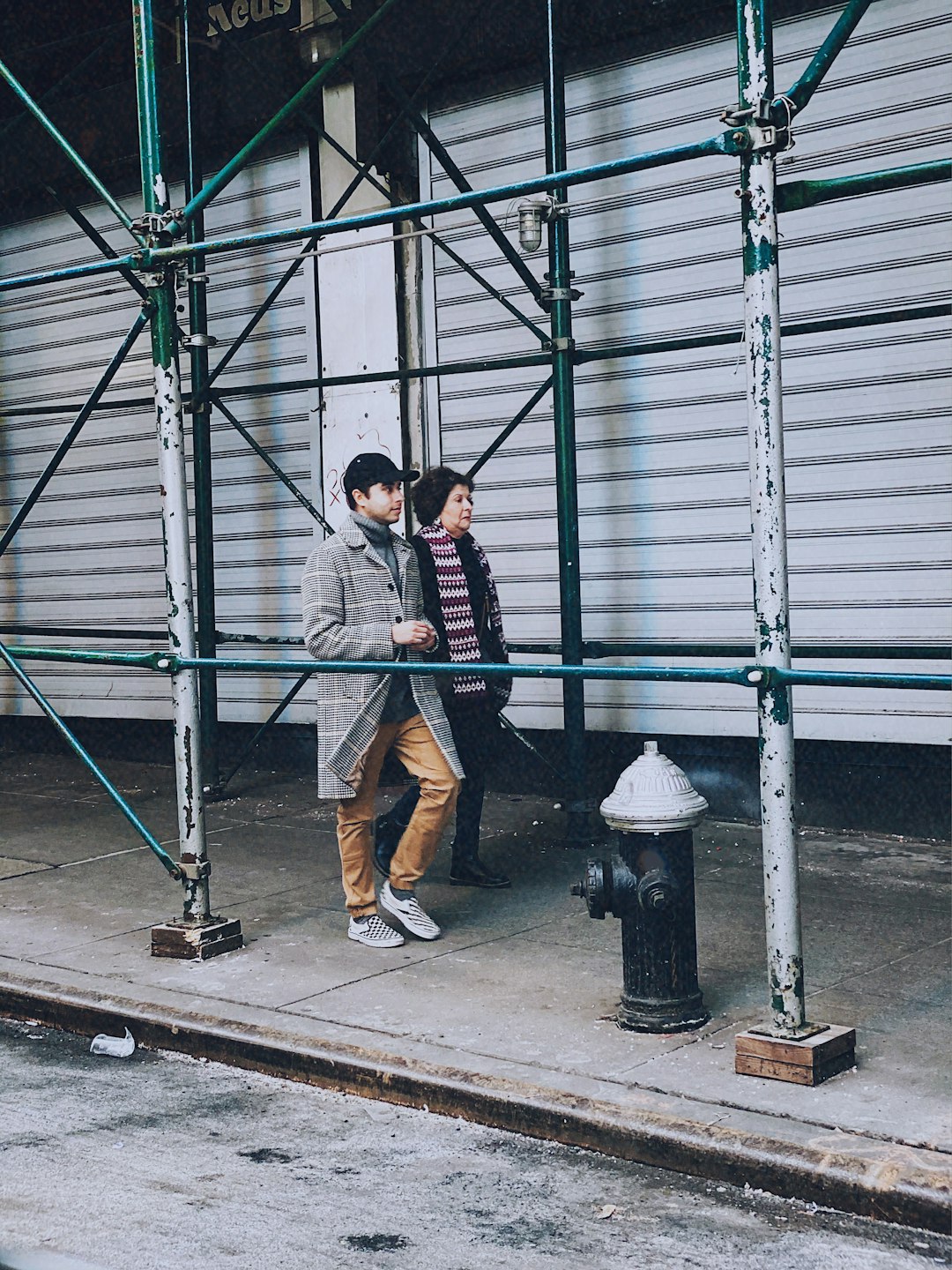 man and woman walking under scaffolds