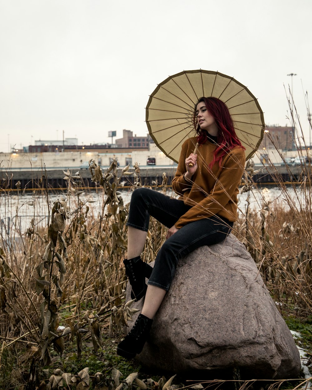 shallow focus photo of woman in brown long-sleeved shirt holding umbrella