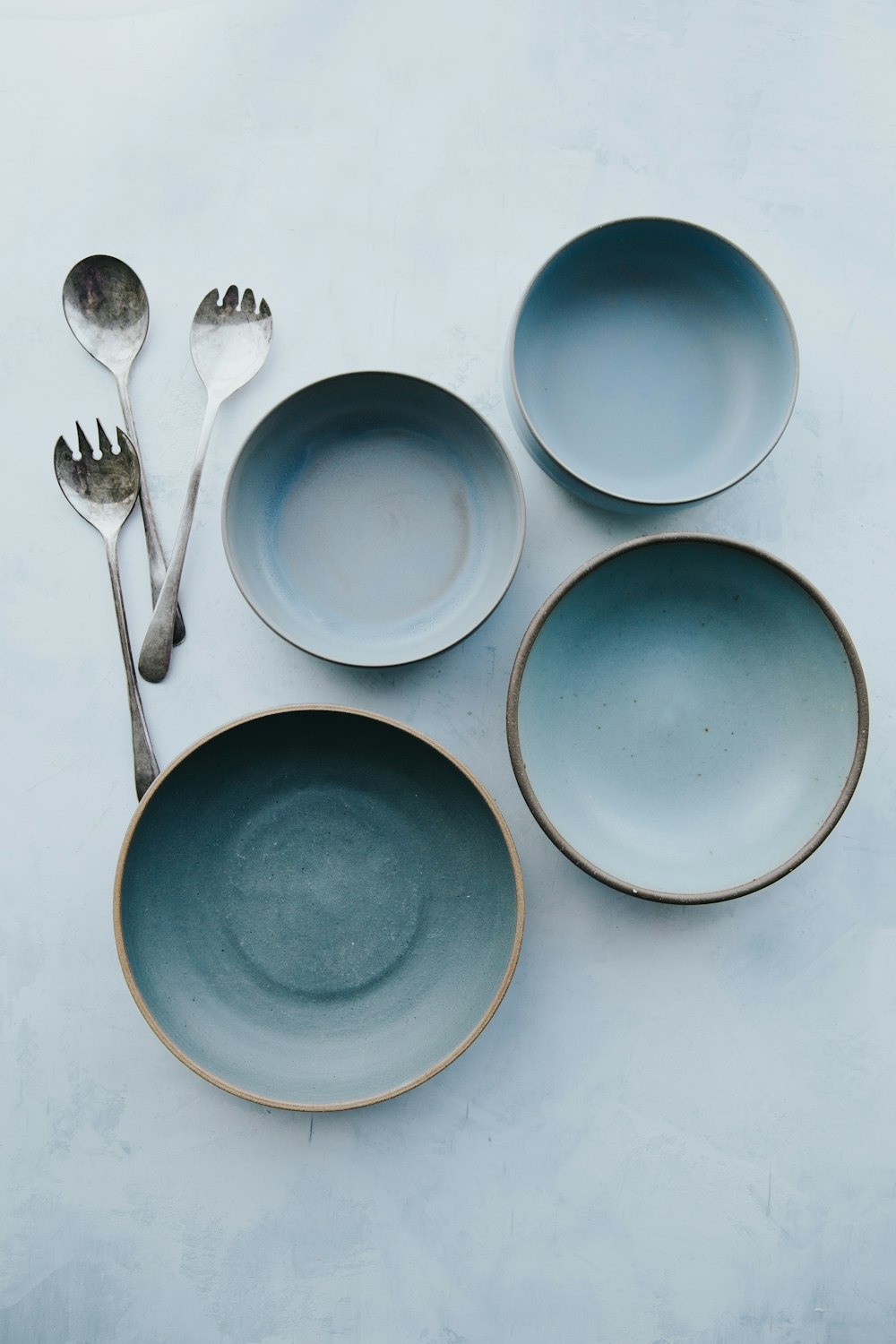 quattro piatti blu assortiti su superficie bianca