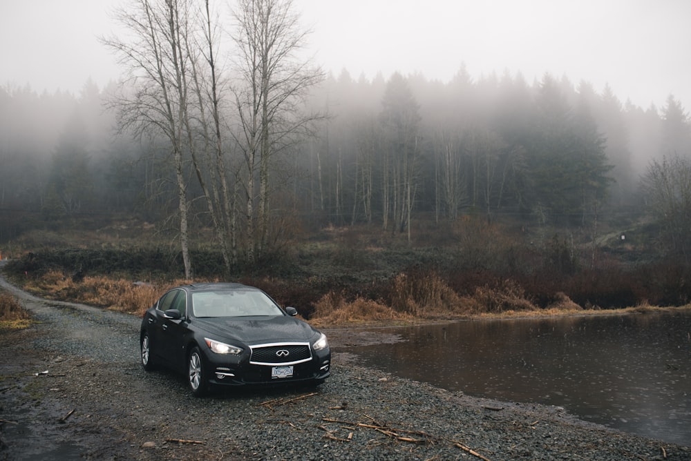 black sedan parked beside body of water during daytime