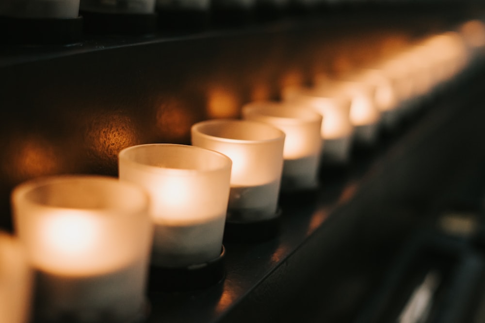 a row of lit candles sitting on top of a shelf