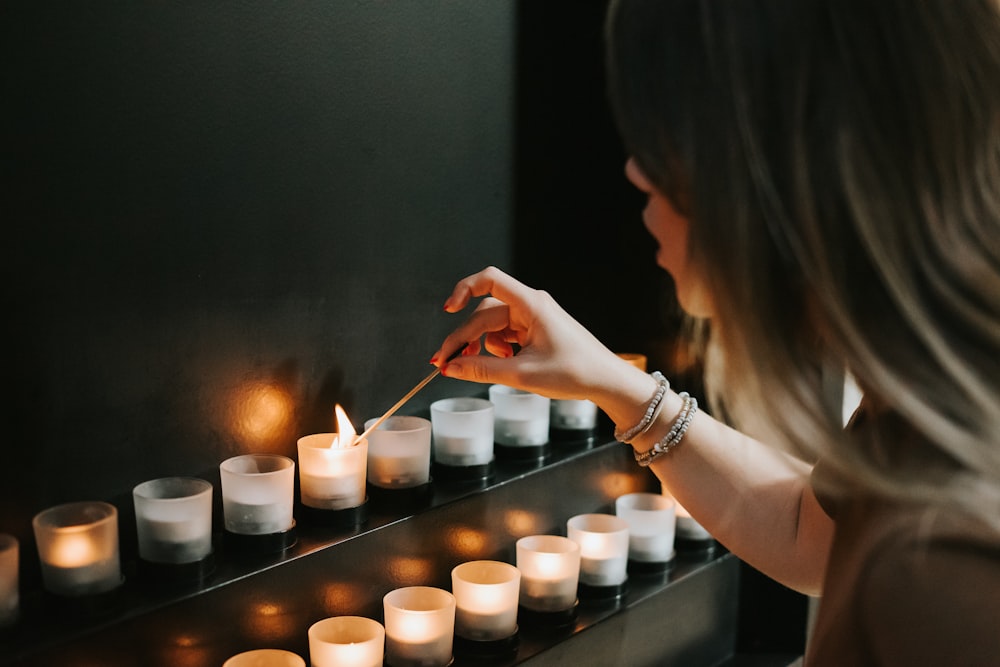 woman lighting a candle beside candles
