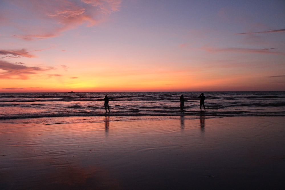 Drei Personen am Meer während der goldenen Stunde