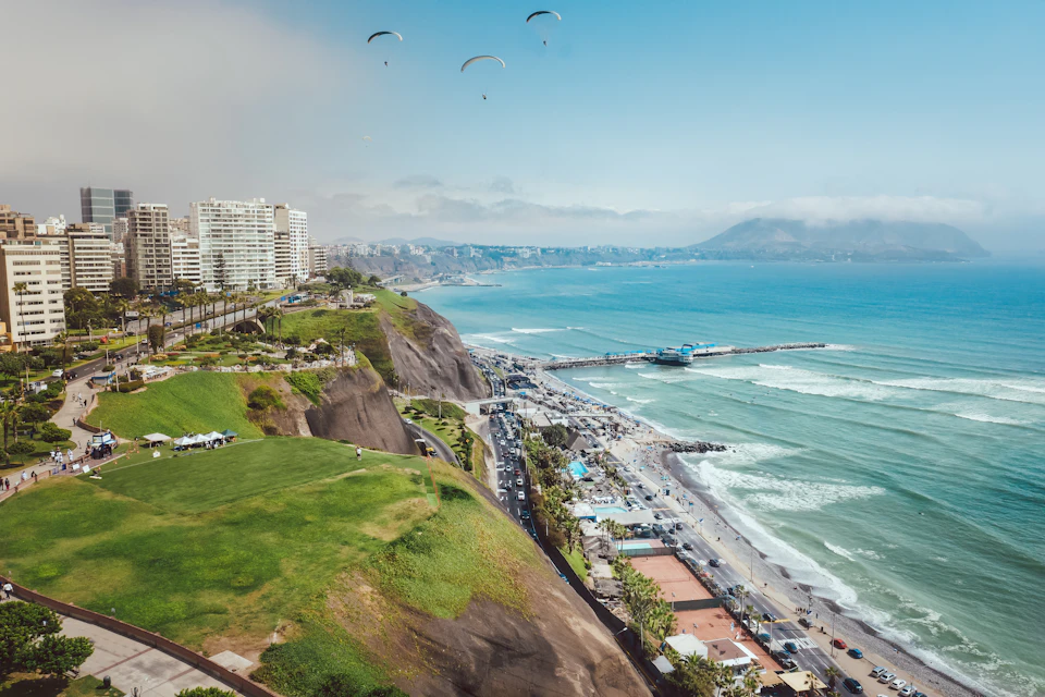 Coastal city perched on a cliff overlooking the ocean with numerous buildings and people