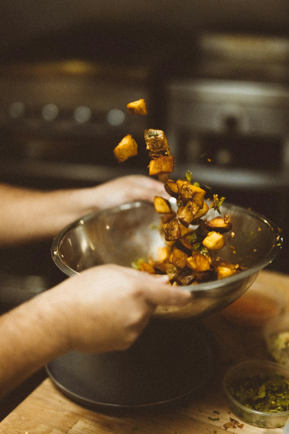 person shaking up a bowl of cooked meat slices