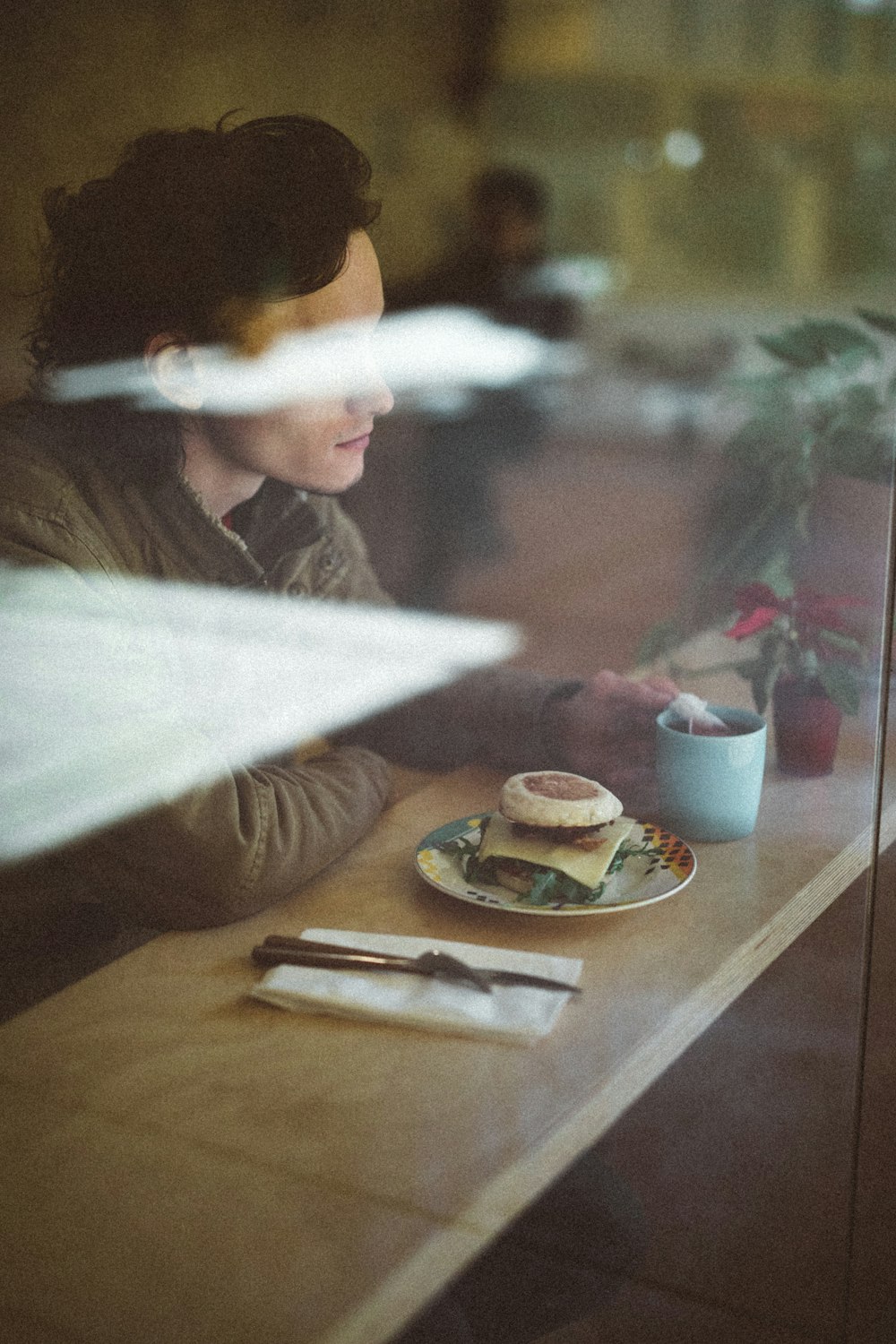 prson sitting in front of table with hamburger on top