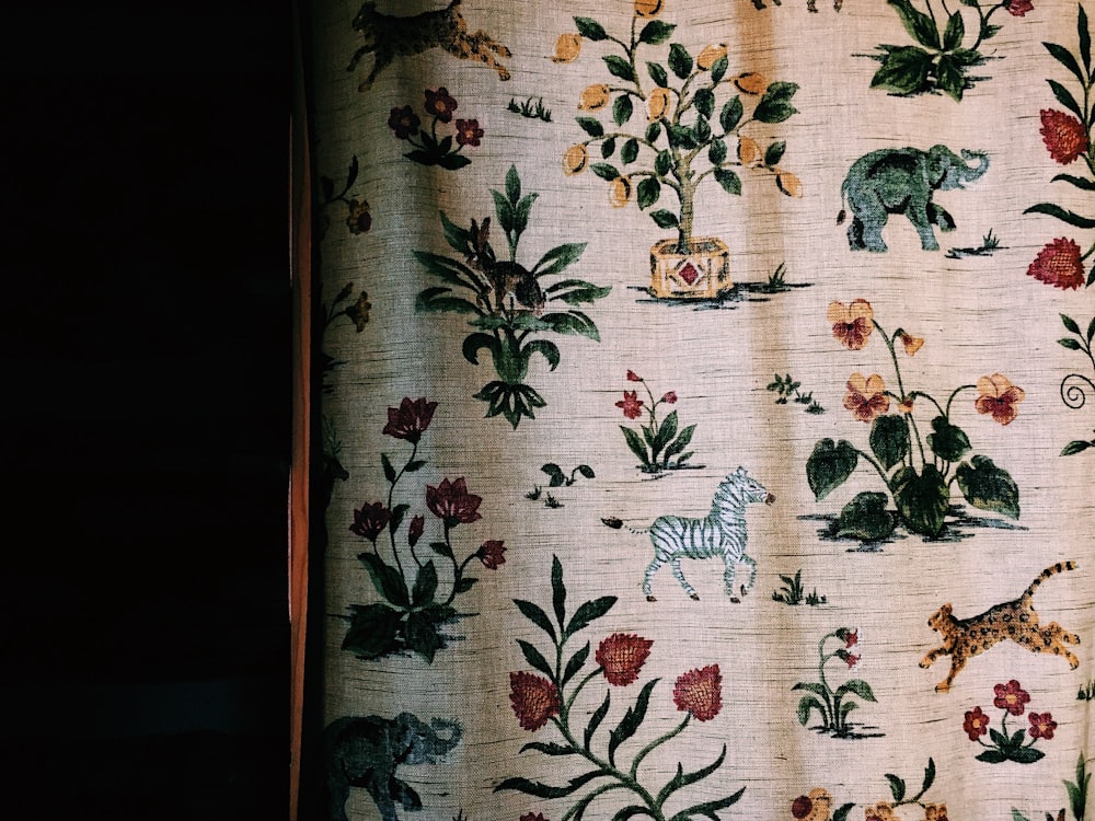 a close up of a curtain with animals and flowers on it