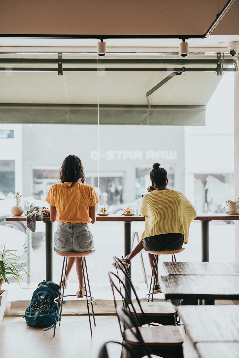 two women in orange and yellow blouses sitting in front of tble