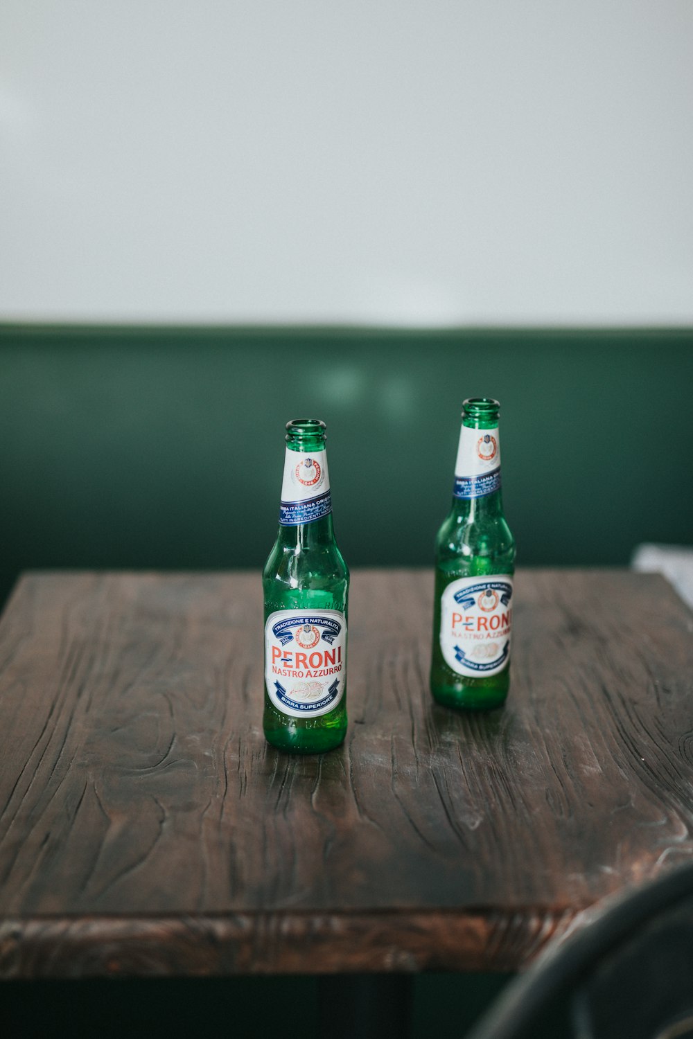 shallow focus photo of green bottles on brown wooden table