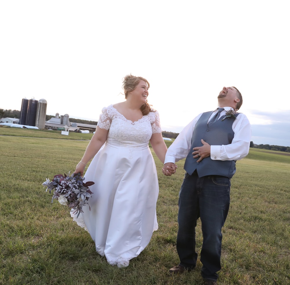 man and woman smiling and holding hands on grass field during day