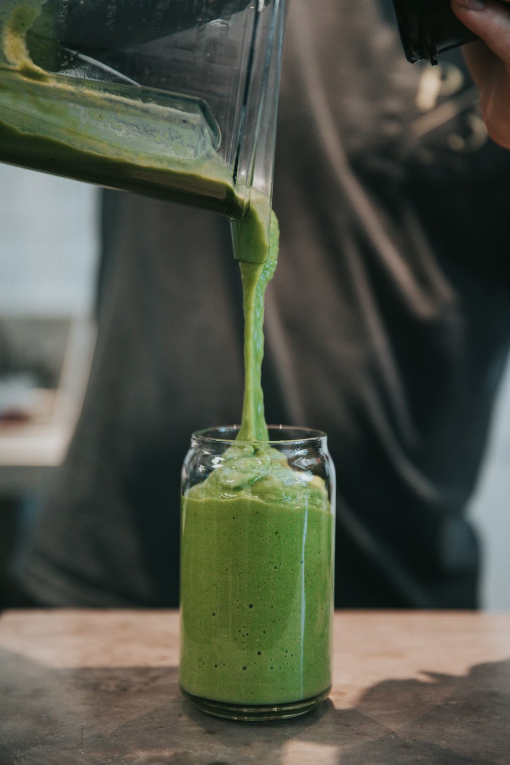 personne versant de la crème dans un verre à boire