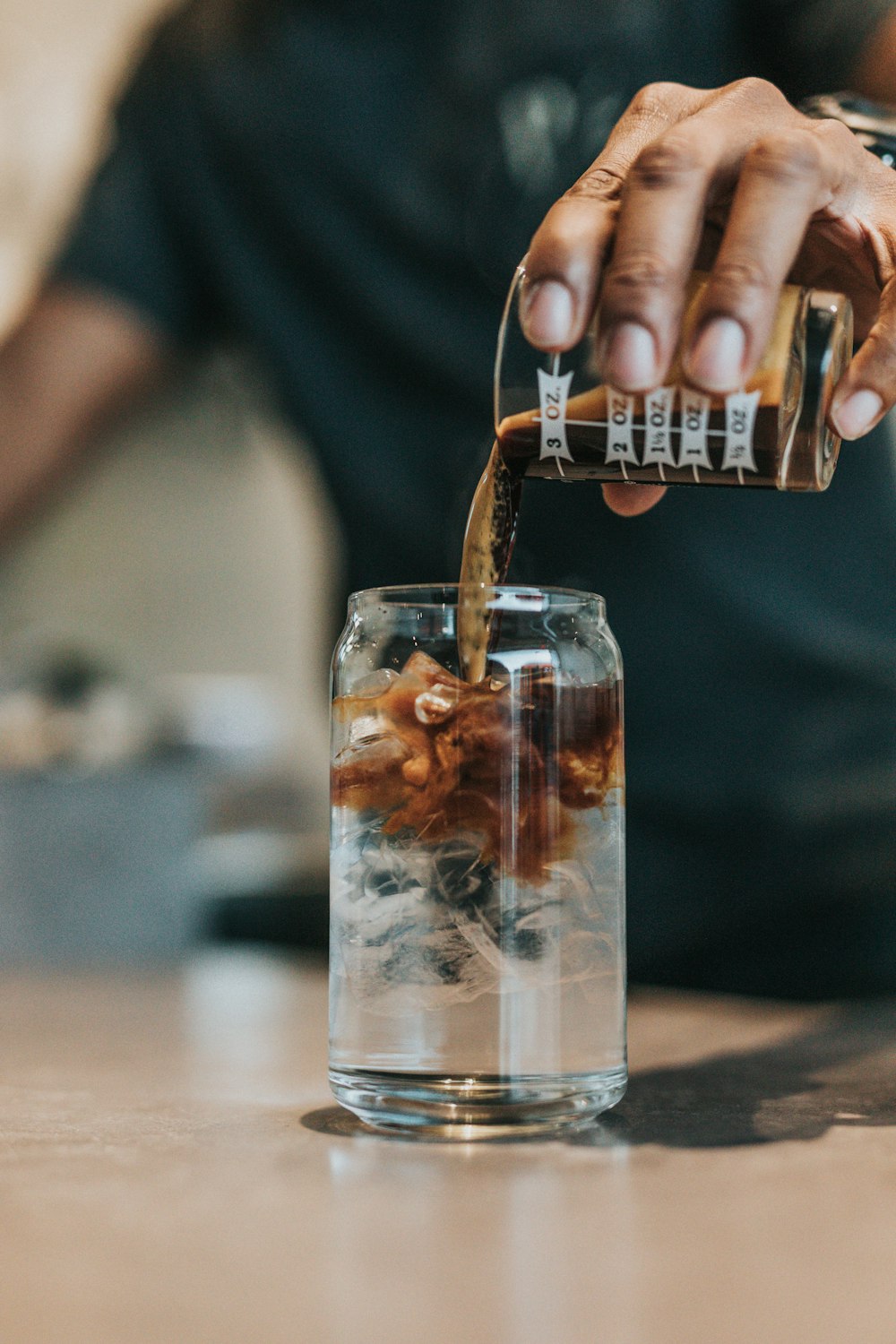 man pouring with brown liquid in glass