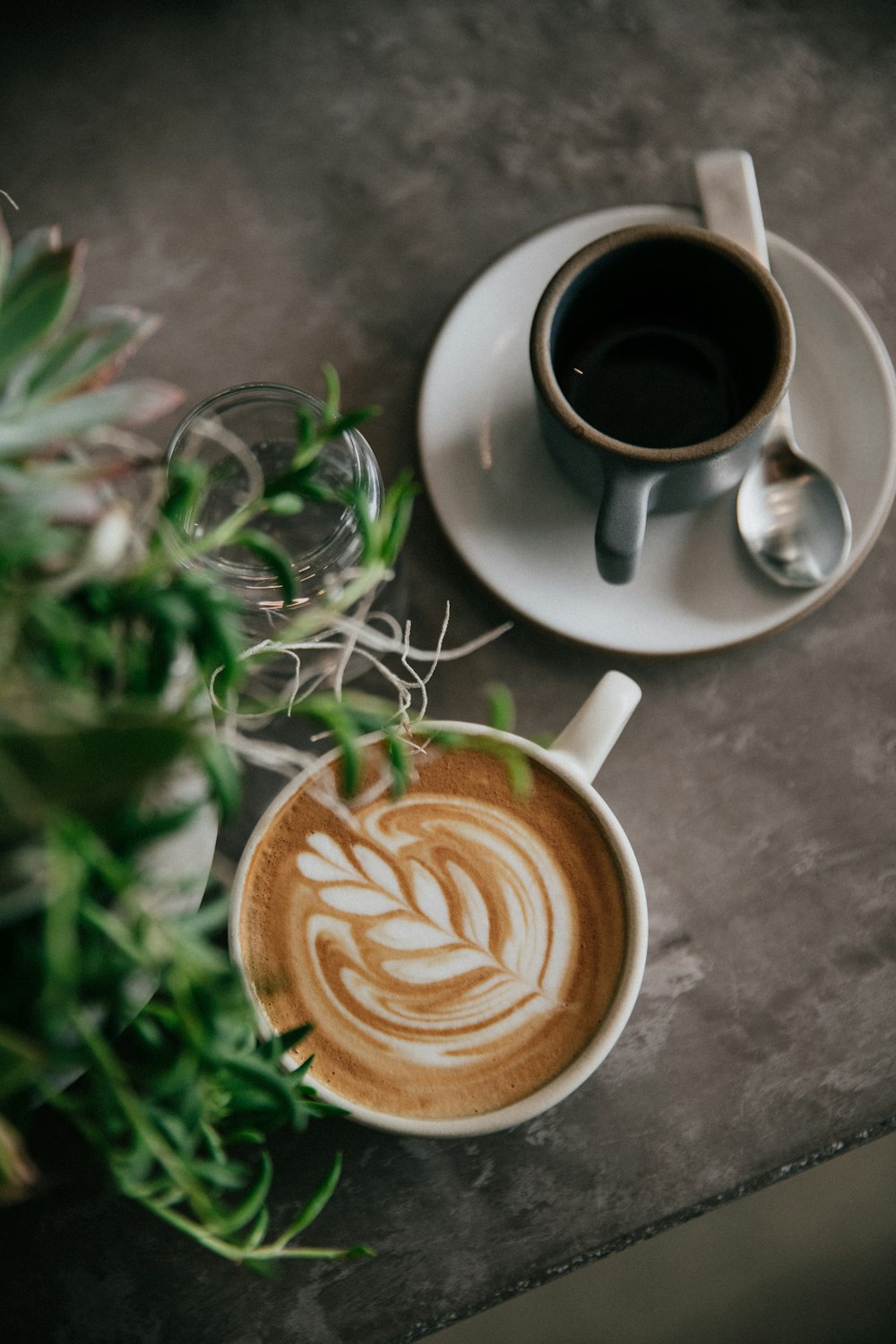 Cappuccino in weißer Keramik-Teetasse neben grauer Teetasse