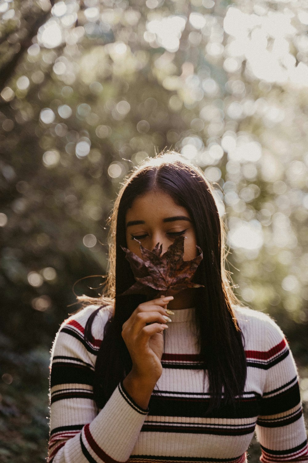 shallow focus photo of woman holding brown leaf