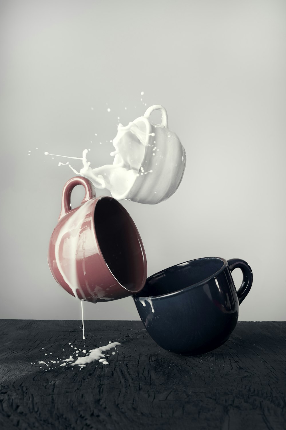 white mug spilling milk on brown and black mugs