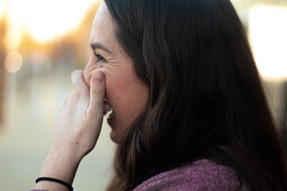 woman covering her nose and mouth while smiling