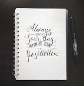 white spiral book with text print beside black pen