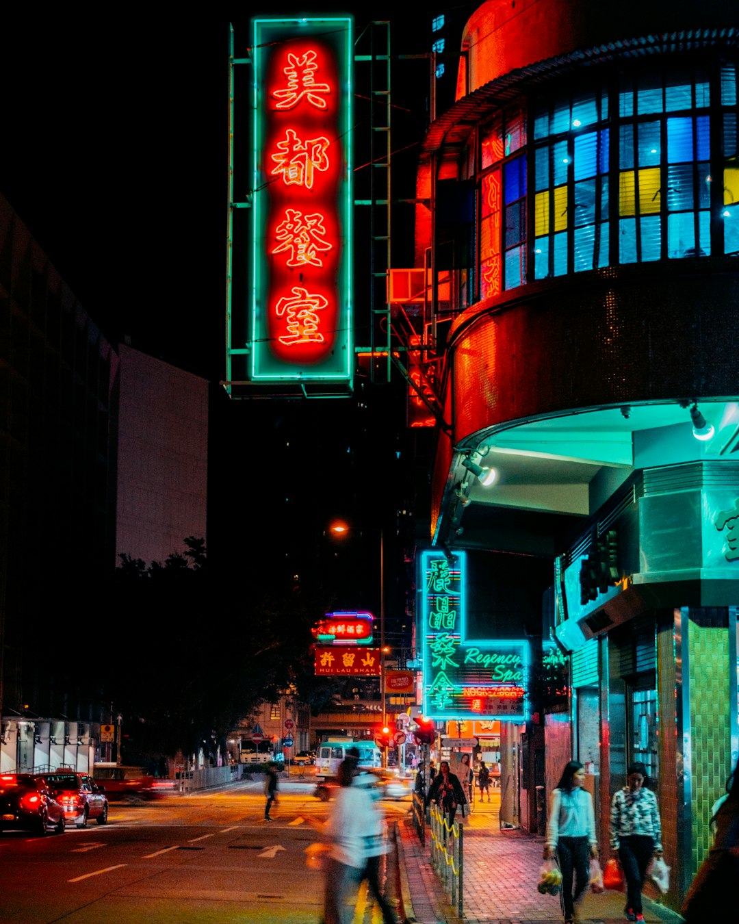 people alking on sidewalk in front of lighted buildings at night